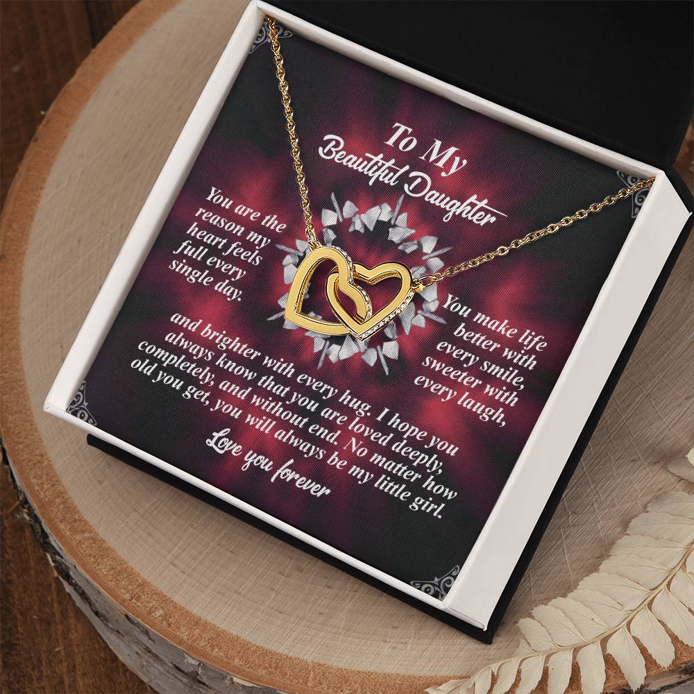 The "Daughter-Every Hug" Interlocking Hearts necklace, adorned with cubic zirconia crystals, rests gracefully in a jewelry box. Accompanied by a heartfelt floral message expressing love to a daughter, it makes for the perfect gift on any special occasion.