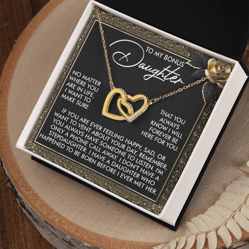 The Daughter-Phone Call - Interlocking Hearts Necklace with a rose gold finish is beautifully presented in a black and white box. The message reads: "TO MY BONUS Daughter... YOU ALWAYS KNOW YOU WILL BE FOREVER LOVED," as it elegantly rests on a wooden surface.