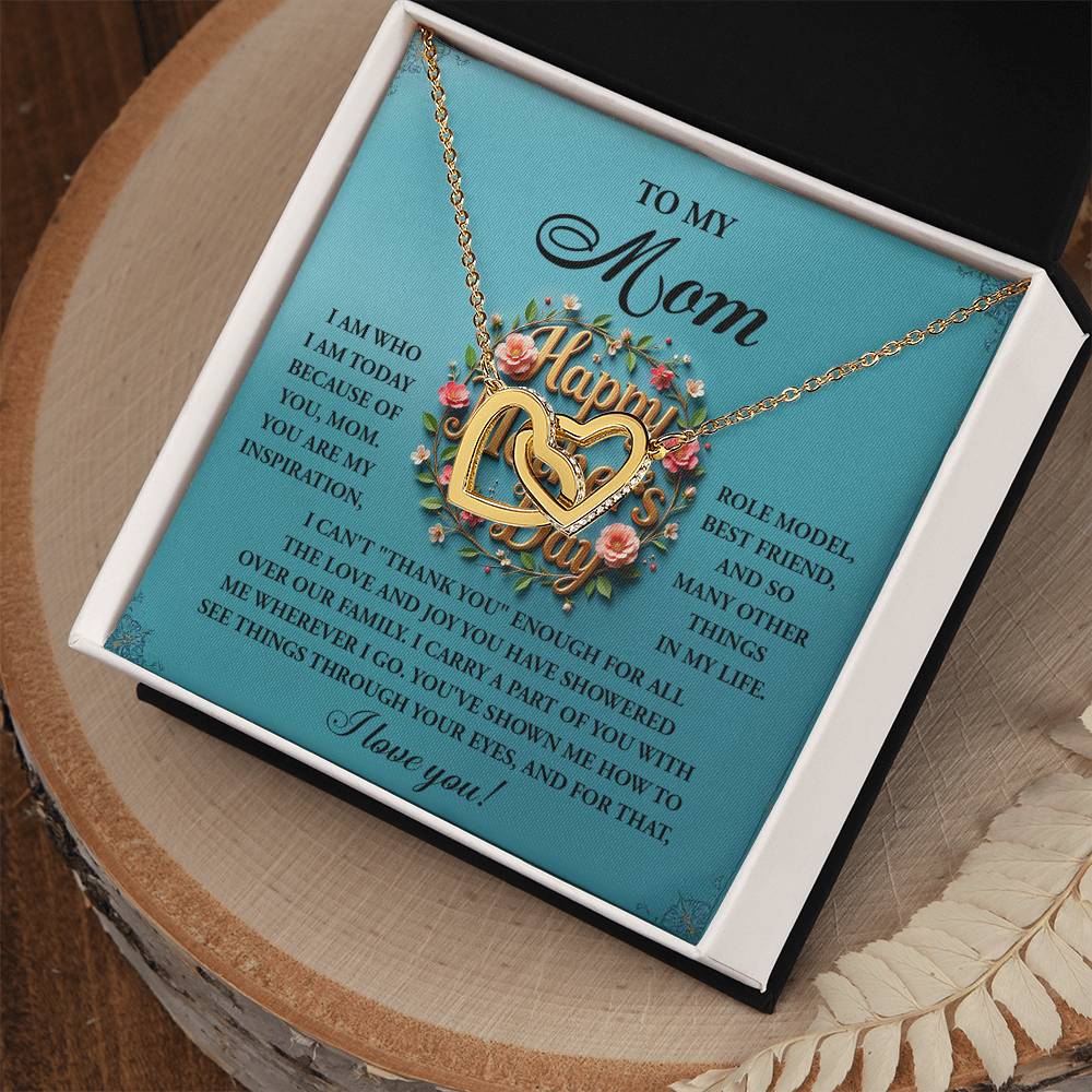 The Mom-Our Family - Interlocking Hearts Necklace, featuring floral details and cubic zirconia crystals, is beautifully presented in a gift box. The lid includes a heartfelt "Happy Mother’s Day" message expressing love and gratitude to "Mom.