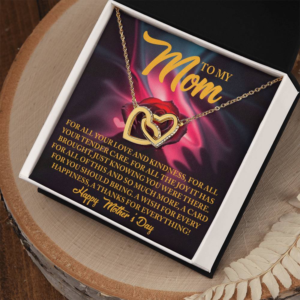 The Mom-Tender Care - Interlocking Hearts Necklace, featuring sparkling cubic zirconia crystals, is beautifully presented in an open black box. The backdrop showcases a heartfelt Mother's Day message with a delicate red rose design—an ideal gift for her.
