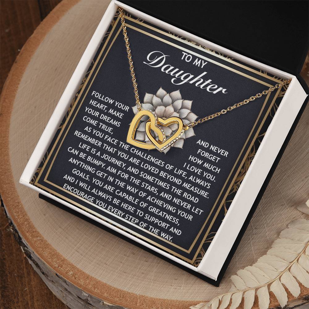 The "Daughter-In The Way - Interlocking Hearts Necklace" features cubic zirconia-adorned hearts in a jewelry box with an inspirational "To My Daughter" card, expressing love and encouragement. It's elegantly finished in rose gold.