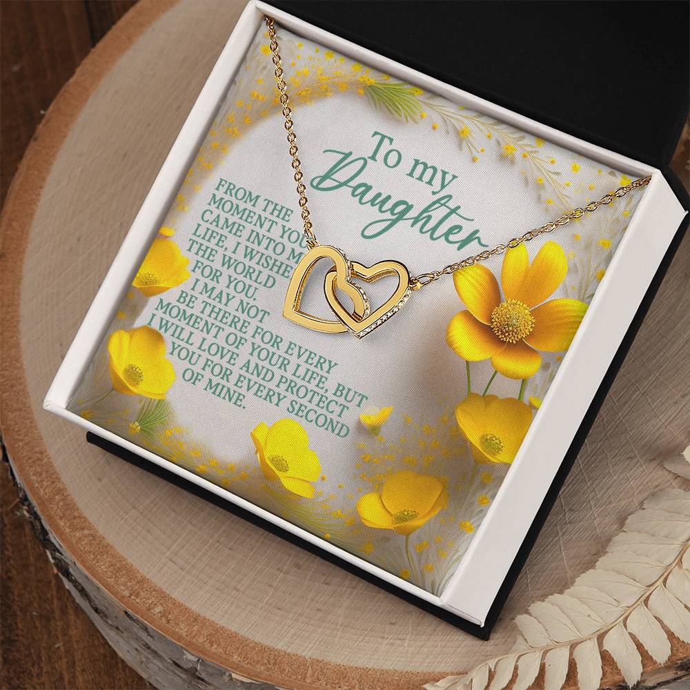 The Daughter-Every Moment Interlocking Hearts Necklace in rose gold rests in an open black box. Yellow flowers and a loving message to a daughter fill the background, enhancing the elegance of the cubic zirconia crystals adorning it.