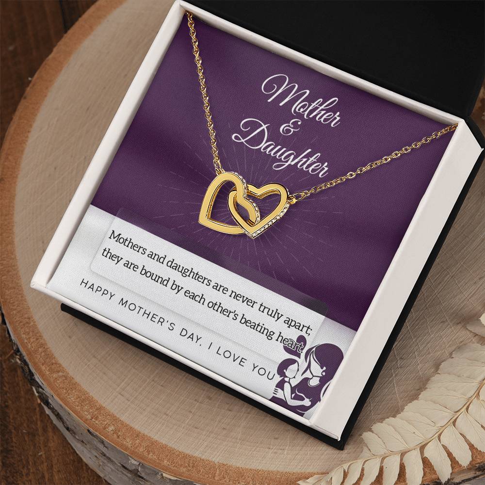 The Mother & Daughter-Never Truly Apart Interlocking Hearts Necklace, adorned with sparkling cubic zirconia, rests in a gift box. The card inside says "Mother & Daughter" and features a touching message about their bond.