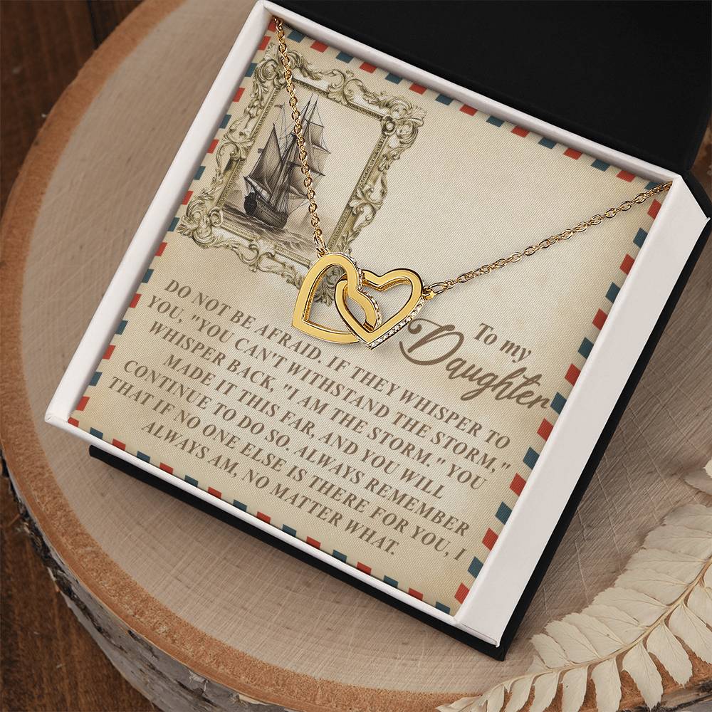 The Daughter-Withstand Storm - Interlocking Hearts Necklace in a rose gold finish is elegantly displayed in a box with a vintage ship illustration card, sharing a heartfelt message about bravery and remembrance against challenges, beautifully set on a wooden surface.