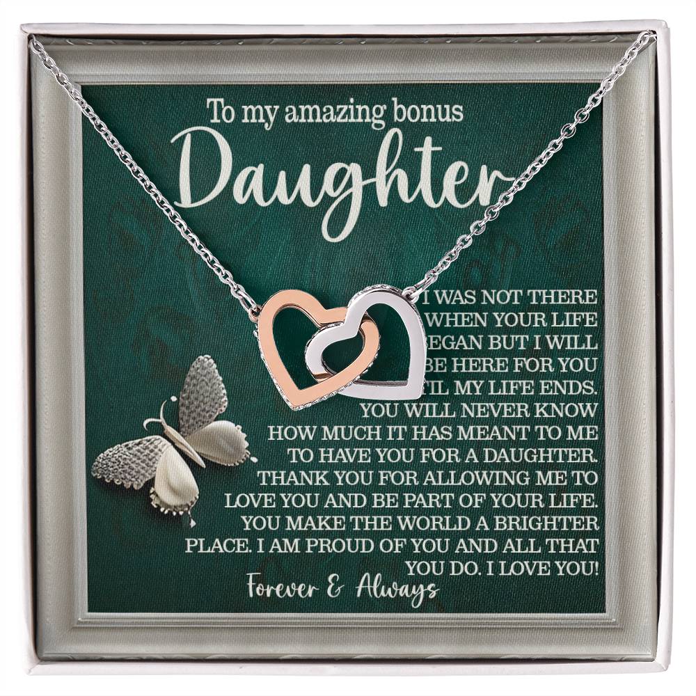 The Daughter-Your Life Interlocking Hearts Necklace in rose gold features heart pendants against a green card reading "To my amazing bonus daughter," adorned with cubic zirconia crystals and a butterfly at the bottom.