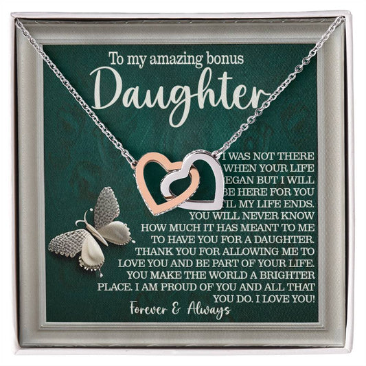The Daughter-Your Life Interlocking Hearts Necklace in rose gold features heart pendants against a green card reading "To my amazing bonus daughter," adorned with cubic zirconia crystals and a butterfly at the bottom.