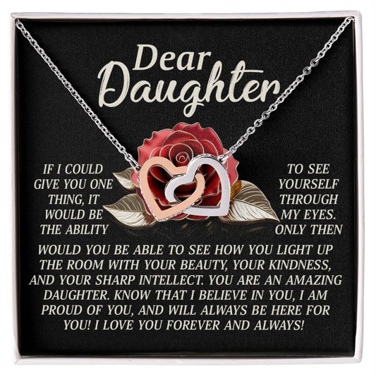 The Daughter-Your Light Interlocking Hearts Necklace, with a rose gold finish, sparkles against a black backdrop with roses. It reads: "Dear Daughter, if I could give you anything, it would be the ability to see yourself through my eyes... You are amazing... I love you forever and always!.