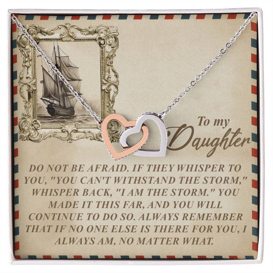 The Daughter-Withstand Storm - Interlocking Hearts Necklace, adorned with cubic zirconia crystals, rests on a card with a ship drawing and the message: "To my Daughter. Do not be afraid..." offering empowering support. A perfect gift for her.
