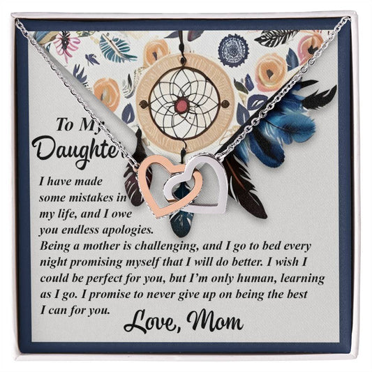 The Daughter-For You Interlocking Hearts Necklace features a rose gold finish and comes with a heartfelt note from a mother to her daughter, expressing love, apologies, and a promise to keep improving. The box's background is adorned with floral and dreamcatcher designs.