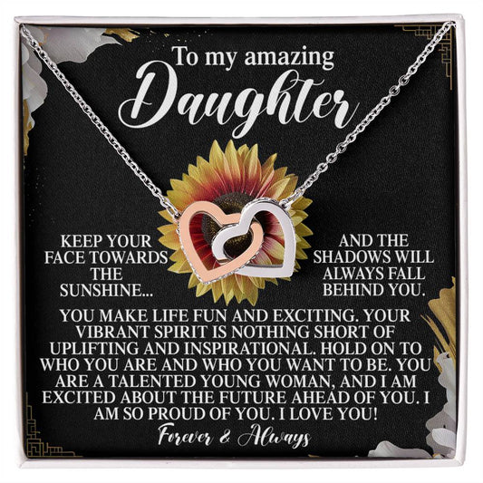 The Daughter-Vibrant Spirit - Interlocking Hearts Necklace sparkles with cubic zirconia crystals against a floral backdrop. A heartfelt message above conveys pride and love, making this elegant gift for her a perfect blend of sophistication and warmth.
