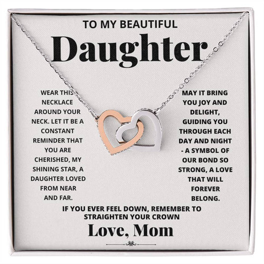 A "To My Daughter, Wear This Necklace - Interlocking Hearts Necklace" with interlocking heart pendants adorned with cubic zirconia crystals on a printed message card from a mother to her daughter, expressing love and encouragement.