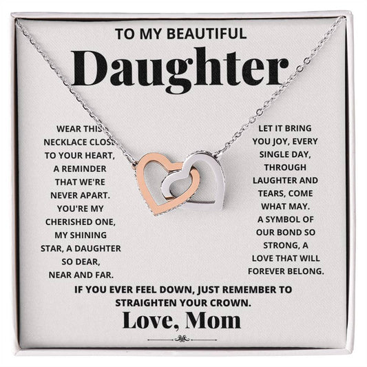 A "To My Beautiful Daughter, Wear This Necklace - Interlocking Hearts Necklace" with interlocking hearts pendants adorned with cubic zirconia crystals, presented in a box with a heartfelt message from a mother to her daughter.