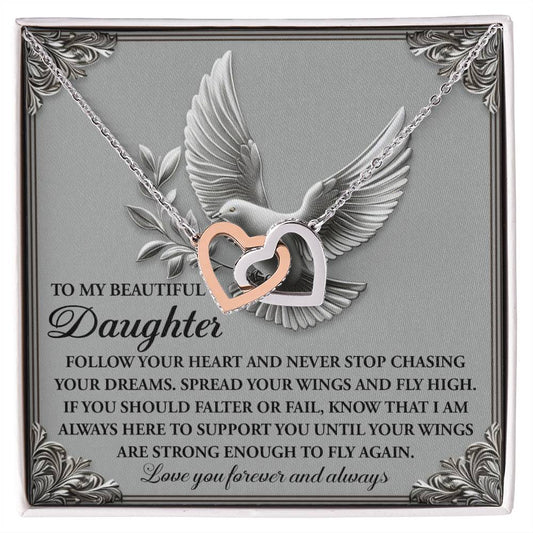 The "Daughter-Your Wings" necklace features two interlocking heart pendants in surgical steel with a rose gold finish, presented on a card embossed with a dove and a message encouraging daughters to pursue their dreams until they can soar independently.
