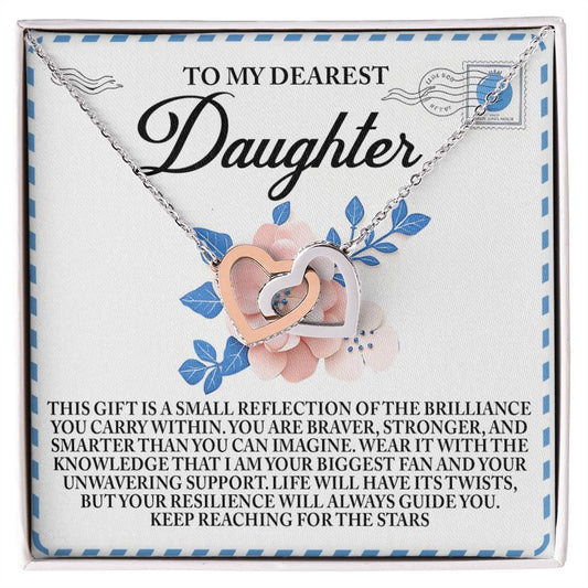 The Daughter-Brilliance Within - Interlocking Hearts Necklace features a stunning rose gold finish and is displayed on a card that reads, "To my dearest daughter," with an inspiring message about her brilliance and strength. The card's background is adorned with blue and pink flowers.