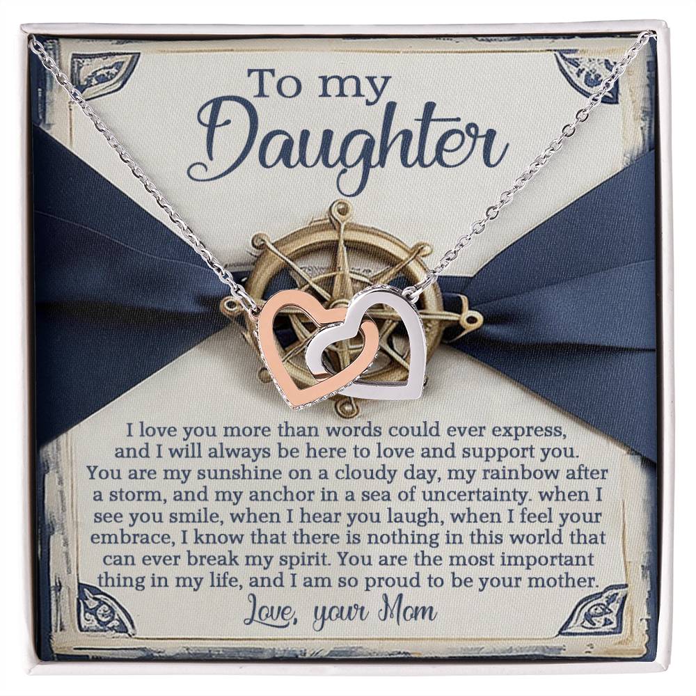 The Daughter-Sunshine Anchor necklace, with rose gold interlocking hearts, rests in a box adorned with cubic zirconia and a heartfelt message from mother to daughter. A ribbon and nautical wheel design add elegance to this loving gift.