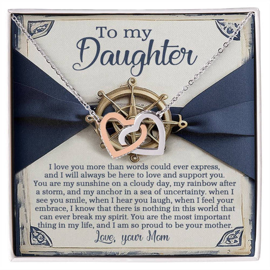 The Daughter-Sunshine Anchor necklace, with rose gold interlocking hearts, rests in a box adorned with cubic zirconia and a heartfelt message from mother to daughter. A ribbon and nautical wheel design add elegance to this loving gift.