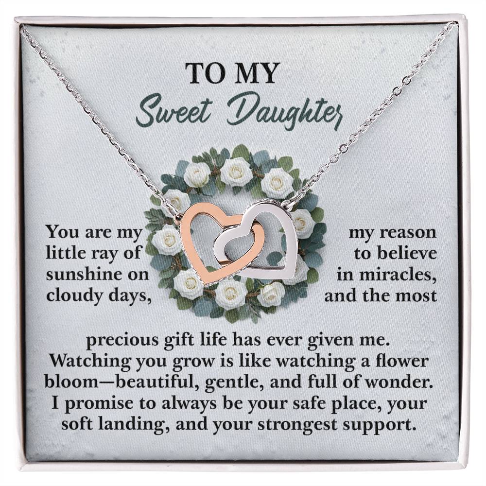 The Daughter-Strongest Support Interlocking Hearts Necklace, with a rose gold finish and intertwined silver elements, is beautifully showcased over a floral wreath. The background includes a heartfelt message for a daughter, conveying love, support, and admiration.