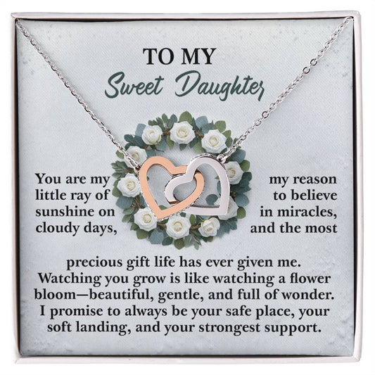 The Daughter-Strongest Support Interlocking Hearts Necklace, with a rose gold finish and intertwined silver elements, is beautifully showcased over a floral wreath. The background includes a heartfelt message for a daughter, conveying love, support, and admiration.