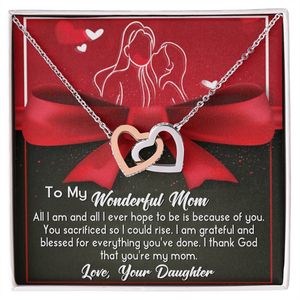 The "To Mom, Because Of You - Interlocking Hearts Necklace," adorned with cubic zirconia crystals and a rose gold finish, is presented on a display card with a heartfelt message from daughter to mom.