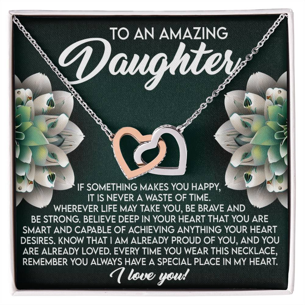 The Daughter-Special Place Interlocking Hearts Necklace, embellished with cubic zirconia and a rose gold finish, is showcased against white flowers. It reads "To An Amazing Daughter" above a touching message ending with "I love you!.