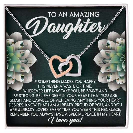 The Daughter-Special Place Interlocking Hearts Necklace, embellished with cubic zirconia and a rose gold finish, is showcased against white flowers. It reads "To An Amazing Daughter" above a touching message ending with "I love you!.