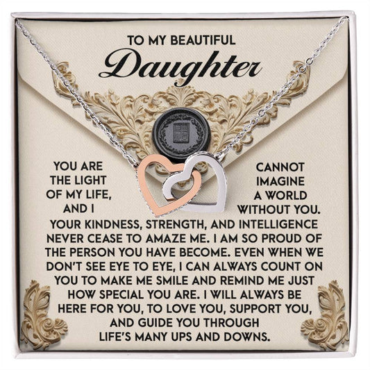 The Daughter-Amaze Me - Interlocking Hearts Necklace, embellished with cubic zirconia crystals and a rose gold finish, elegantly rests on a decorative card featuring a heartfelt message for your daughter.