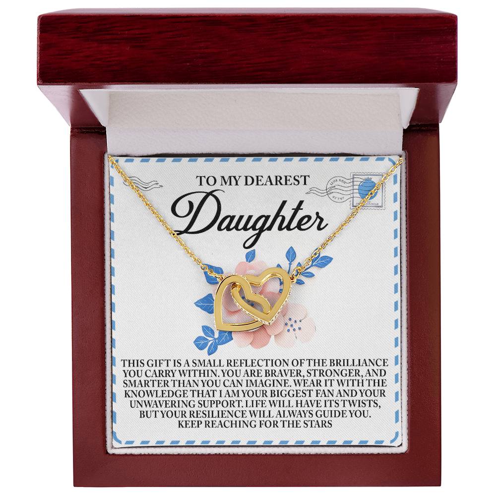 The Daughter-Brilliance Within - Interlocking Hearts Necklace, adorned with cubic zirconia crystals, comes in a floral wooden box labeled "To My Dearest Daughter," featuring a soft white interior and an inspirational message of love, strength, and support.