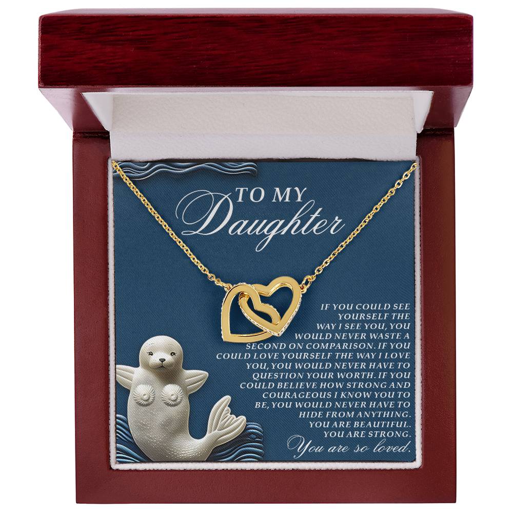 The Daughter-So Loved - Interlocking Hearts Necklace with a rose gold finish is elegantly presented in a jewelry box. The open lid reveals a heartfelt message card for a daughter and features an illustration of a smiling seal holding a heart.