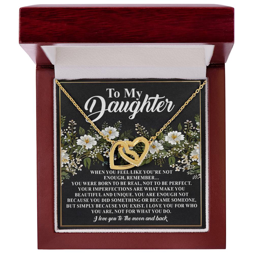 The Daughter-What You Do Interlocking Hearts Necklace, with a rose gold finish and cubic zirconia crystals, is elegantly presented in an open box. The box features "To My Daughter" and a heartfelt message amid white flowers and greenery.