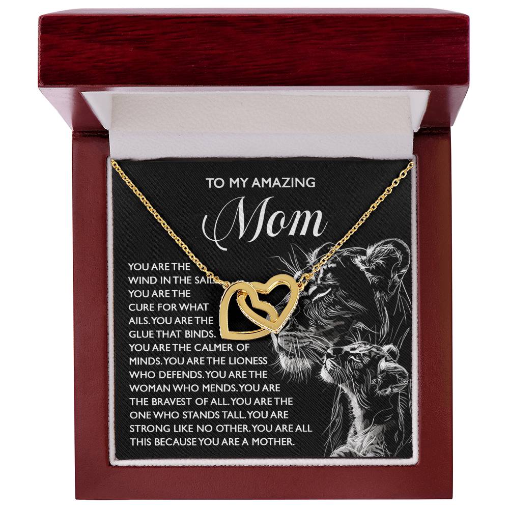 The Mom-The Cure Interlocking Hearts Necklace features a rose gold finish, presented in a red gift box adorned with a black and white lioness and cub illustration on the inside cover, along with heartfelt text dedicating this thoughtful gift to an amazing mom.