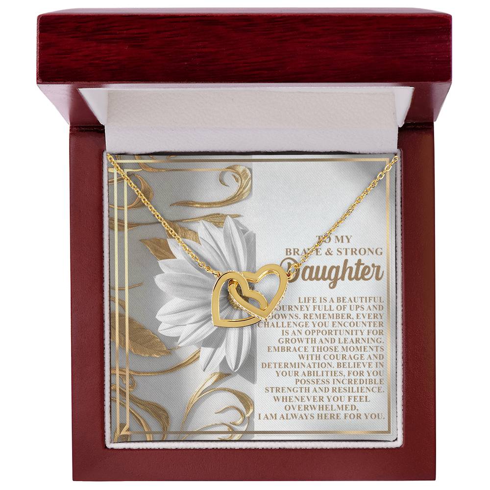 The Daughter-Here For You - Interlocking Hearts Necklace, embellished with cubic zirconia crystals, is beautifully displayed in an open red jewelry box. A floral-decorated message card behind it delivers an inspiring note for a daughter.