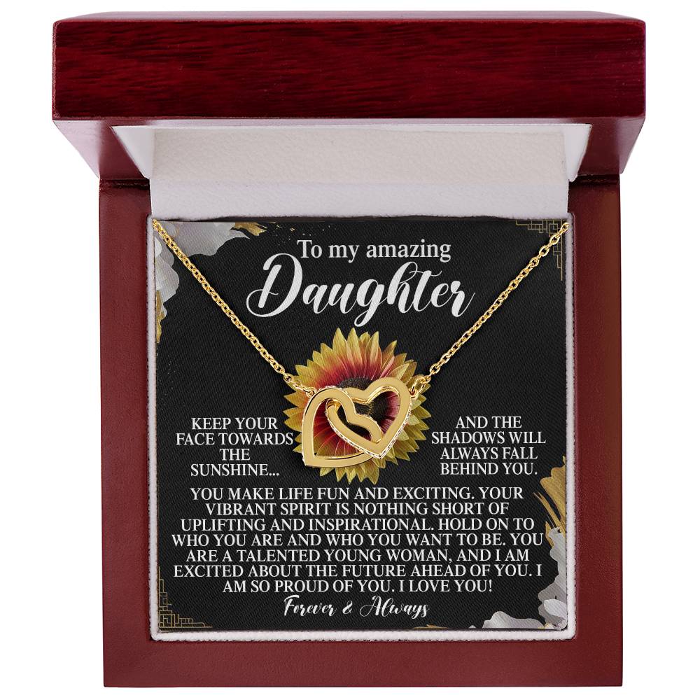 The Daughter-Vibrant Spirit - Interlocking Hearts Necklace features rose gold-finished interlocking heart pendants in a red jewelry box, against a sunflower-themed backdrop with a touching message to a daughter about pride, love, and future encouragement.