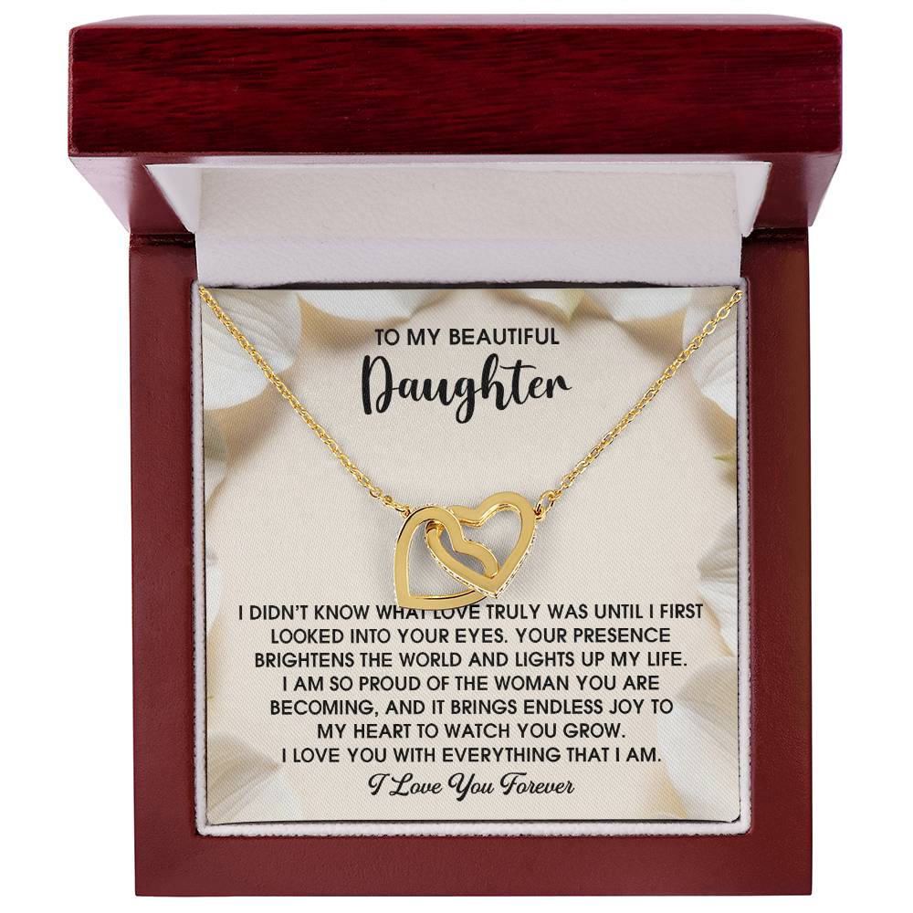 The Daughter-Into Your Eyes Interlocking Hearts Necklace, adorned with cubic zirconia crystals, comes in a red box and features an inscription expressing love and pride for a daughter, making it the perfect gift for her.
