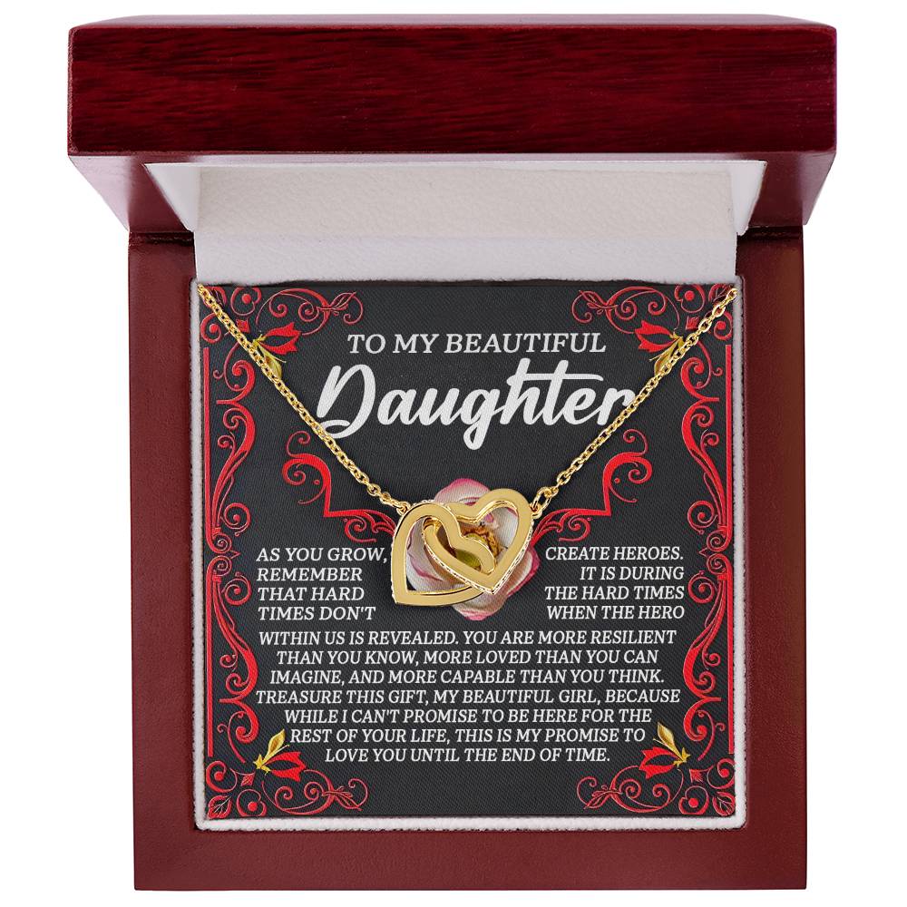 The Daughter-Hard Times Interlocking Hearts Necklace, with heart pendants, comes in a decorative jewelry box. Its interior features an inspirational message emphasizing love, resilience, and support. The ornate design is enhanced with cubic zirconia crystals and red accents.