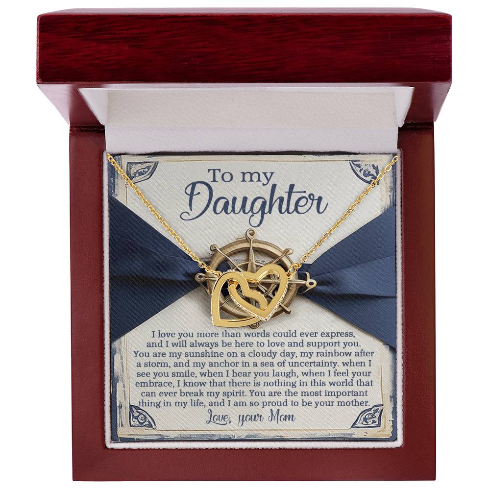 The Daughter-Sunshine Anchor - Interlocking Hearts Necklace, featuring a gold and rose gold finish with sparkling cubic zirconia crystals, is elegantly presented in a red jewelry box. A heartfelt message from mom to daughter, adorned with nautical-themed graphics, expresses love and support.