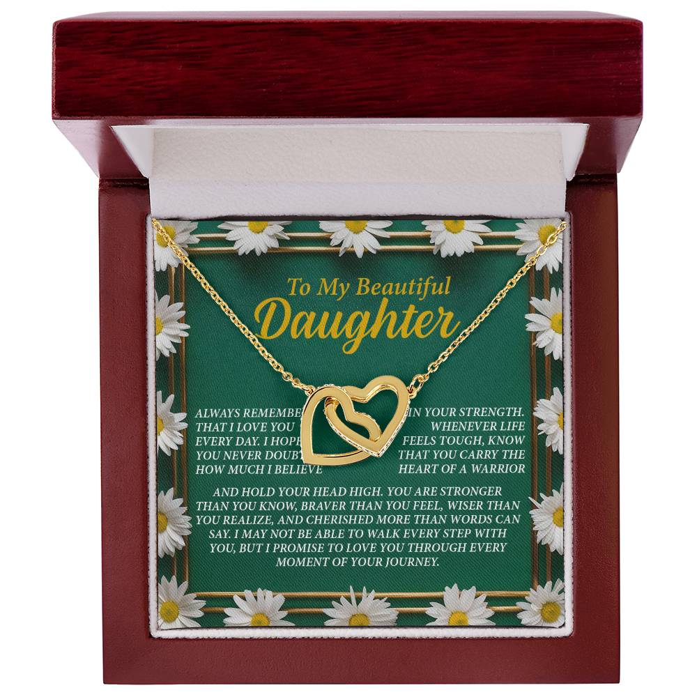 The Daughter-Your Journey Interlocking Hearts Necklace, featuring a rose gold finish, is elegantly presented in a wooden jewelry box and rests on a green card with white daisy borders and an affectionate message for your daughter.