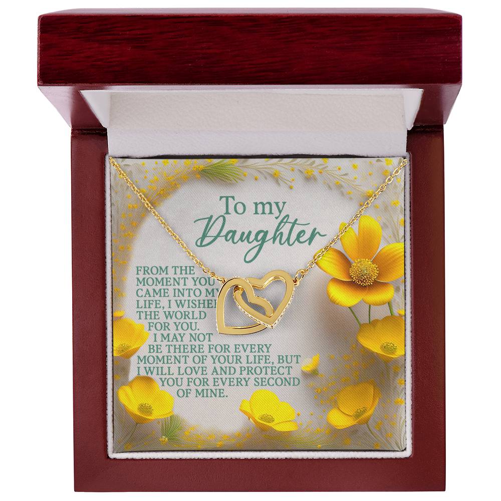 The Daughter-Every Moment Interlocking Hearts Necklace features a heart-shaped pendant with sparkling cubic zirconia crystals and a rose gold finish. It's presented in a red box with a dedication card, adorned with yellow flowers and a heartfelt message about love and protection.