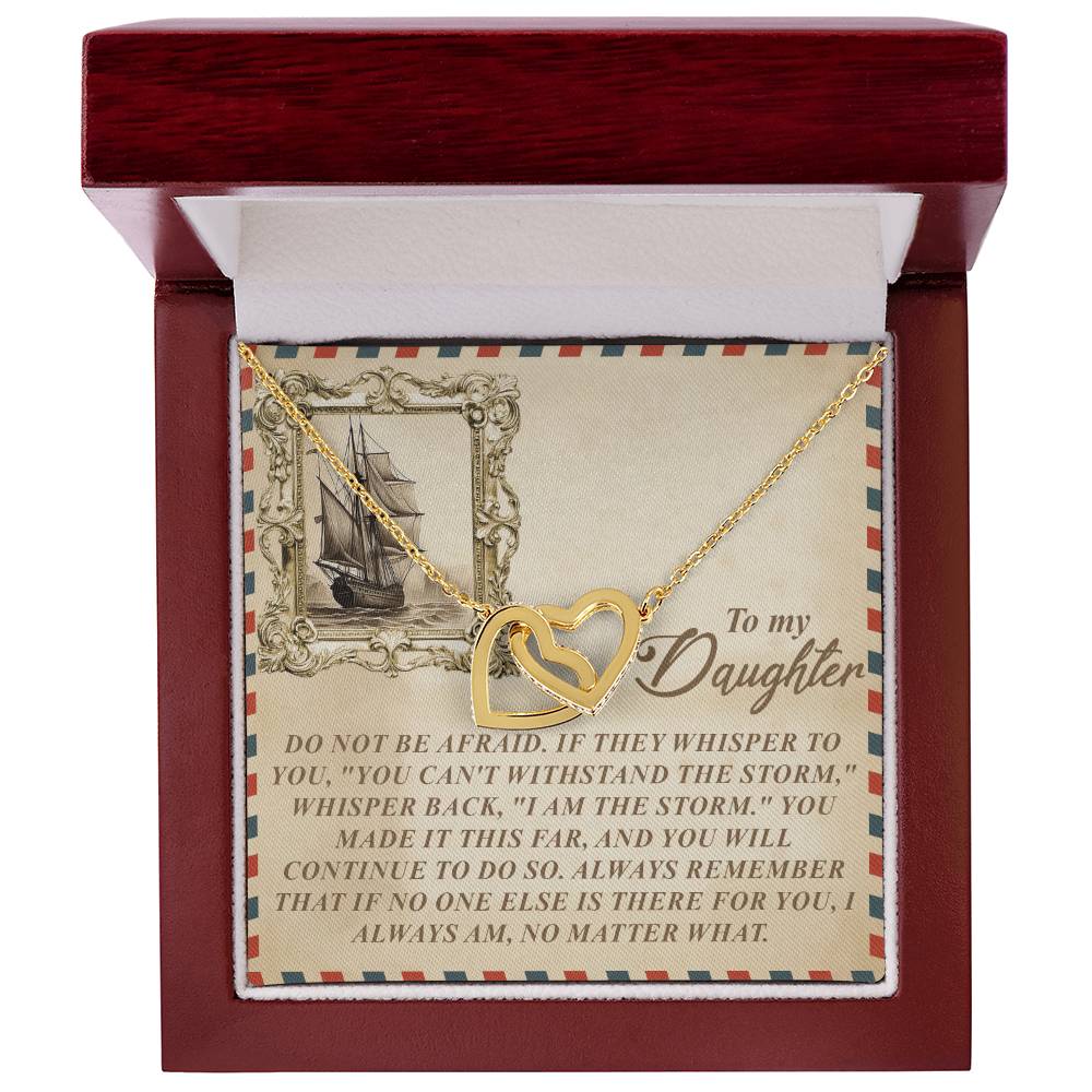 A Daughter-Withstand Storm Interlocking Hearts Necklace in an 18k yellow gold finish lies in a red velvet-lined box. The cubic zirconia-adorned pendant comes with a heartfelt ship illustration and words of courage and strength for your daughter.