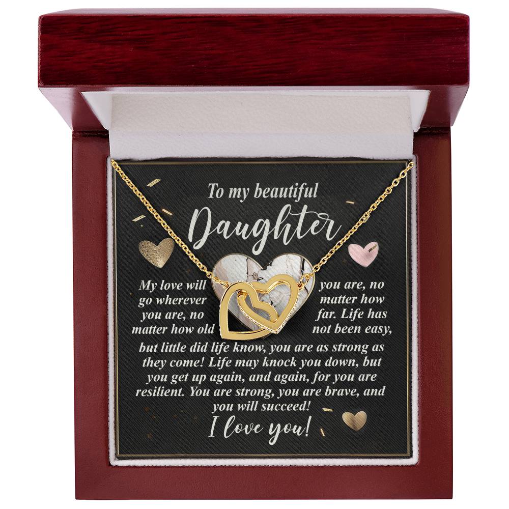 The "Daughter-Your Strength - Interlocking Hearts Necklace," featuring sparkling cubic zirconia crystals, is elegantly presented in an open wooden box. Set against heartfelt words for a daughter, it symbolizes love, resilience, and encouragement.