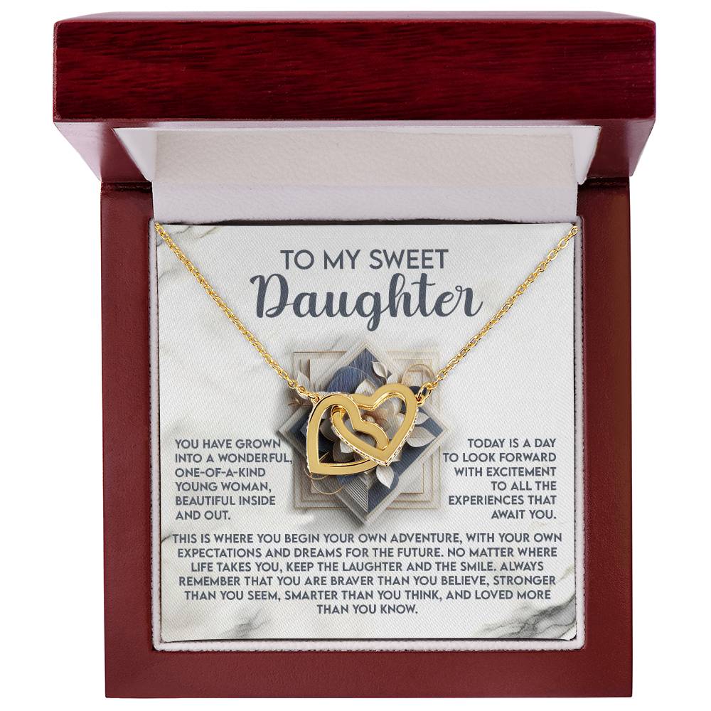 The Daughter-For The Future - Interlocking Hearts Necklace, featuring cubic zirconia crystals, is placed inside a red jewelry box. The lid says "To my sweet daughter," followed by an inspirational message about growth, love, and resilience.