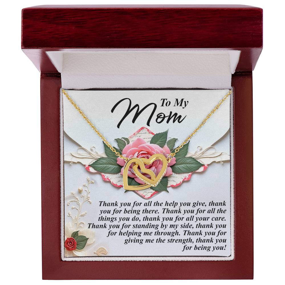 The Mom-Being You - Interlocking Hearts Necklace in rose gold rests in an open red velvet box, inscribed with "To My Mom" and a heartfelt message. Delicate floral designs adorn the background, adding charm.