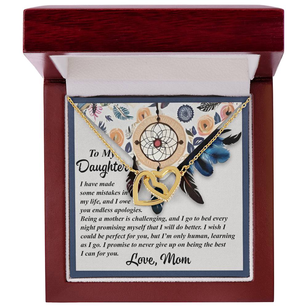 The Daughter-For You - Interlocking Hearts Necklace in rose gold finish is elegantly showcased in a wooden jewelry box. It comes with a heartfelt message adorned with floral and dreamcatcher designs, enhanced by sparkling cubic zirconia crystals.