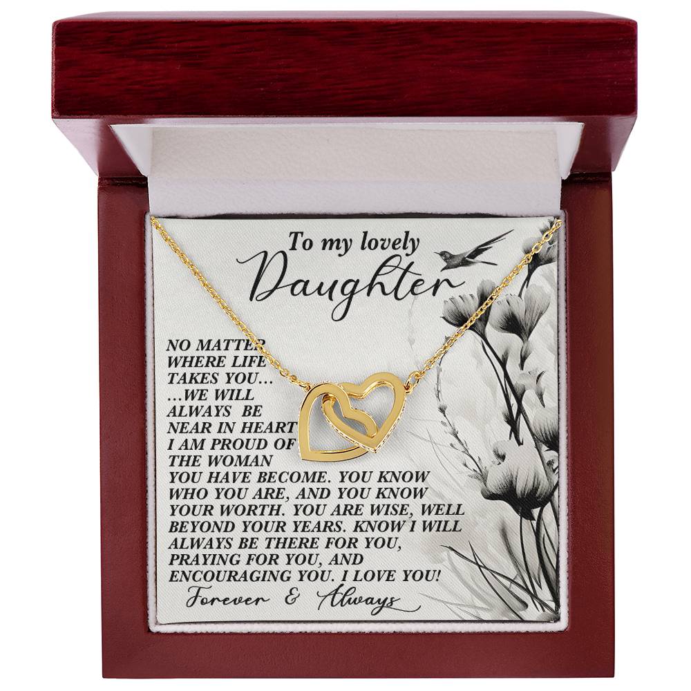The "Daughter-Heart Near - Interlocking Hearts Necklace" in a wooden jewelry box features a rose gold finish and floral design with cubic zirconias. A heartfelt message to your daughter is displayed inside, emphasizing love and pride.