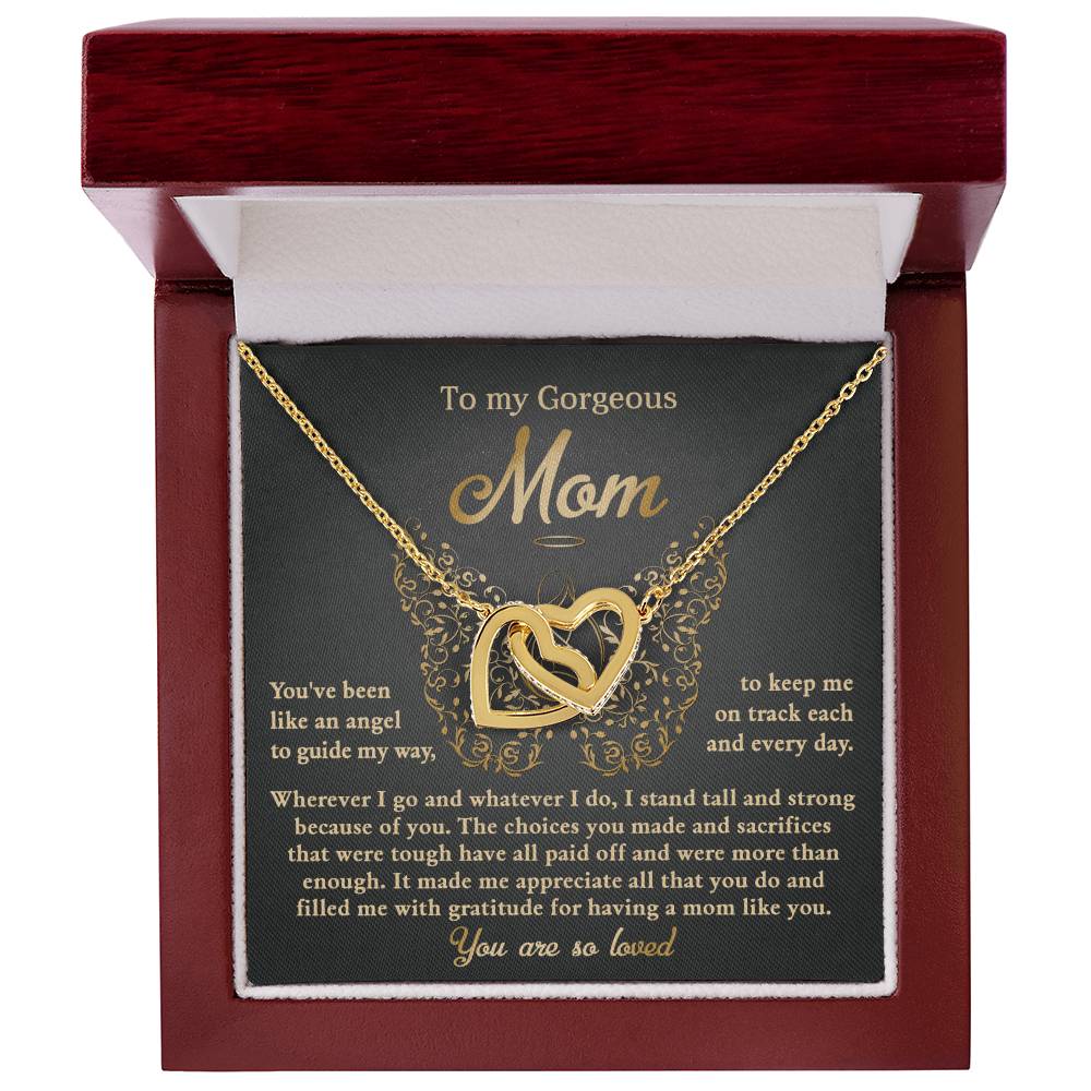 The "To Mom, Like An Angel" Interlocking Hearts Necklace features gold and cubic zirconia crystals, presented in a red velvet-lined box with a card that reads, "To my Gorgeous Mom, You are so loved," capturing love and appreciation beautifully.