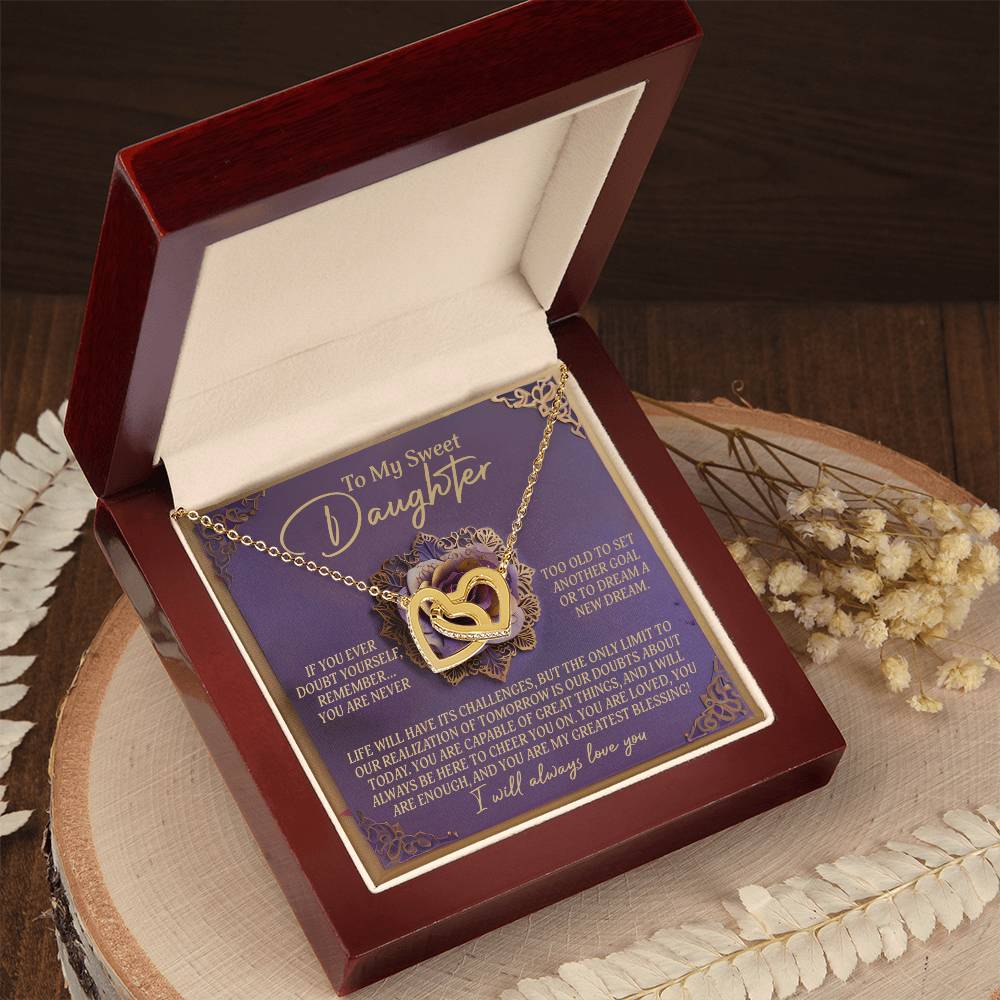 The Daughter-Greatest Blessing - Interlocking Hearts Necklace with a rose gold finish rests in its box next to dried flowers on the table. The lid features a heartfelt message expressing love and guidance to a daughter.