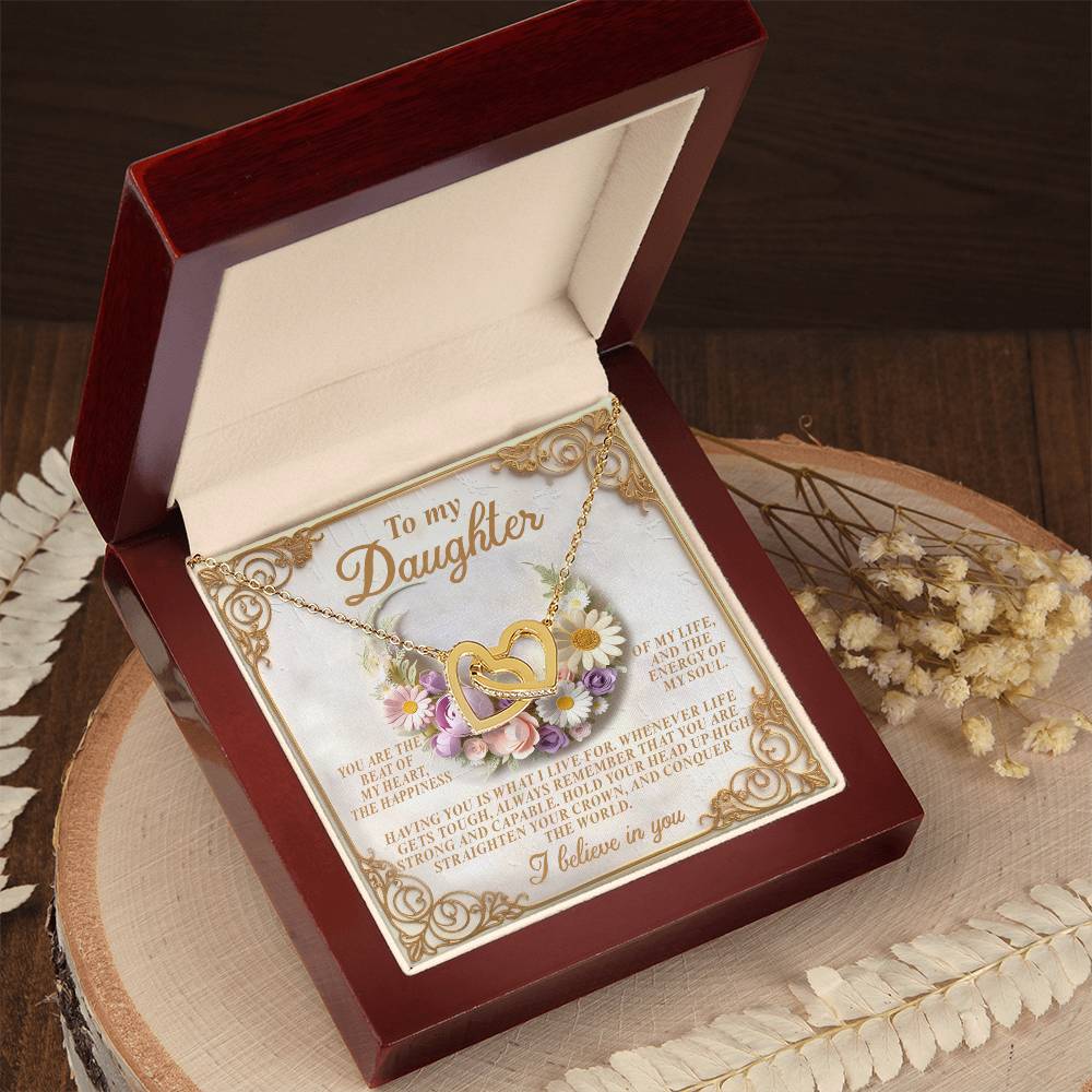 The Daughter-Heart Happiness - Interlocking Hearts Necklace showcases intertwined pendants with a rose gold finish, presented in a wooden box adorned with floral designs and a heartfelt "To my Daughter" message card amid dried flowers.