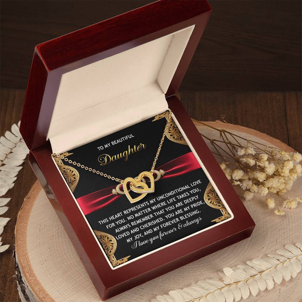 In an open red box, the "Daughter-Love For You - Interlocking Hearts Necklace" with shimmering cubic zirconia charms accompanies a loving message to a daughter about love and blessings. It rests on a wooden surface adorned with dried flowers.