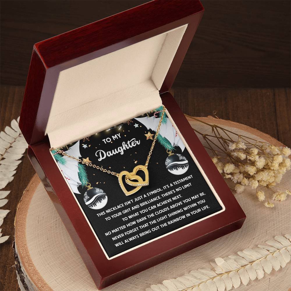 Daughter-The Rainbow - Interlocking Hearts Necklace featuring cubic zirconia crystals, elegantly presented in a wooden gift box with a message that reads "To My Daughter." The open box is displayed on a wooden surface, surrounded by dried flowers.