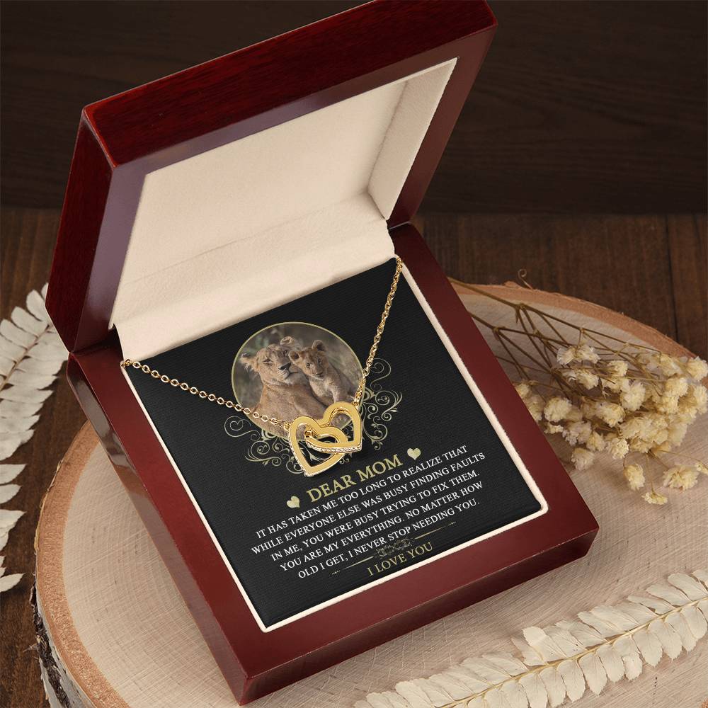A personalized gift awaits in an open wooden box: the "To Mom, My Everything - Interlocking Hearts Necklace" adorned with cubic zirconia crystals. The lid displays a heartfelt message to "Dear Mom.