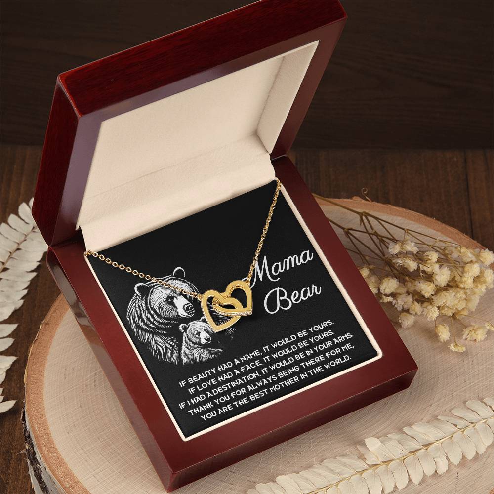 The "To Mom, In Your Arms" Interlocking Hearts Necklace showcases gold hearts with cubic zirconia in an open red jewelry box. The interior features a bear illustration and a "Mama Bear" message, making it an ideal personalized gift.